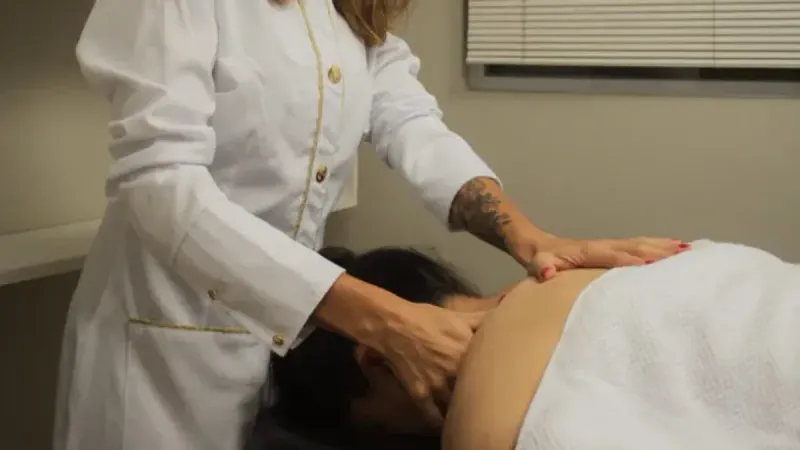 Fisioterapeuta aplicando liberação miofascial na região cervical e nas costas de uma paciente