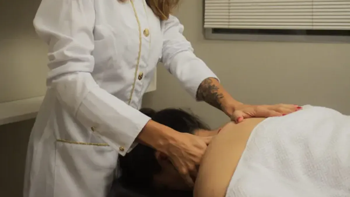 Fisioterapeuta aplicando liberação miofascial na região cervical e nas costas de uma paciente